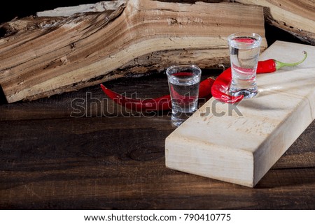 Vodka in a glass of hot pepper on the rustic background