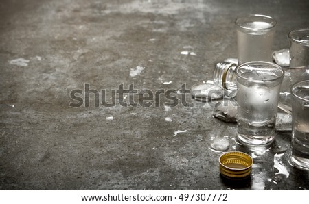The vodka glass with ice. On the stone table.