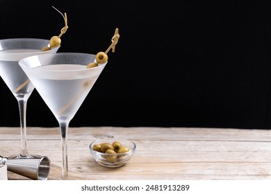 Vodka martini cocktail with vodka and vermouth and green olives on wooden table. Copy space