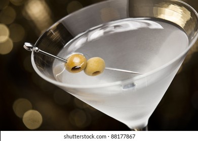 Vodka Martini with olive garnish in front of a gold glitter background