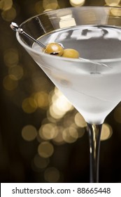 Vodka Martini with olive garnish in front of a gold glitter background