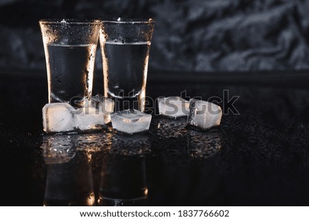 Vodka in shot glasses on dark background.