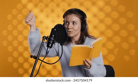 Voice actor looking to producer off camera to know when to start narrating book, producing audiobook. Narrator doing counting on fingers gesturing before starting digital recording of novel, camera B