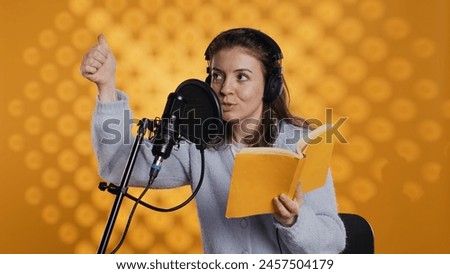 Voice actor looking to producer off camera to know when to start narrating book, producing audiobook. Narrator doing counting on fingers gesturing before starting digital recording of novel, camera B