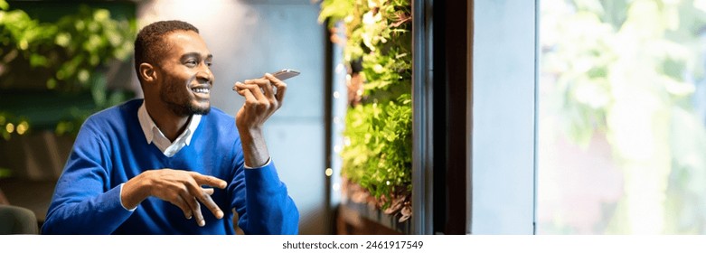 Voice Search. Happy black man using voice assistant on mobile phone or calling on smartphone at cafe, copy space, web-banner - Powered by Shutterstock