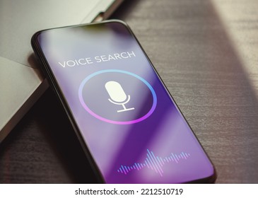 Voice search, speech recognition and sound detect app concept with close up smartphone lying on a black wooden table and sound wave, microphone, voice search text on the screen.