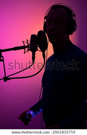 Voiceover artist actor recording voice overs in professional audio studio with large diaphragm cardioid microphone.