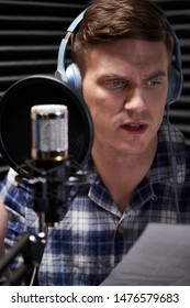 Voiceover Artist In Recording Studio Reading From Script Into Microphone                          