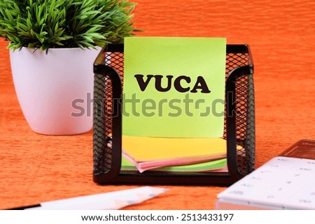 Volatility Uncertainty Complexity Ambiguity. VUCA text on a yellow sticker in a black stand on an orange background
