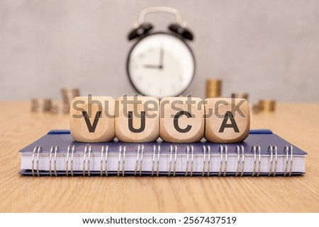 Volatility Uncertainty Complexity Ambiguity - VUCA - text on wooden blocks, stock image. background money and oclock