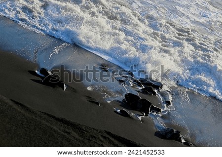 Volcanic Black Beach with Black Rocks and White Water Waves