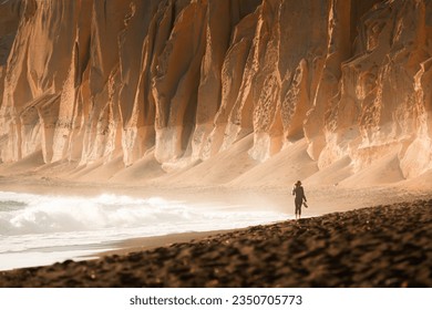 Volcanic cliffs on Vlichada beach in Santorini island, Greece. Woman walking along the beach. at sunset. Famous travel destination - Shutterstock ID 2350705773