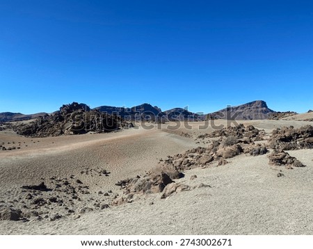 Volcanic desert and lava fields in Teide National Park, Tenerife, Canary Islands, Spain. Arid mountain landscape with rocks, sand, and clear blue sky on a sunny day.