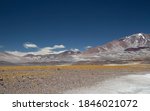 Volcanic landscape in the Andes mountain range. View of Volcano Incahuasi, arid valley, golden grassland and natural salt flat in San Francisco pass, Catamarca, Argentina.