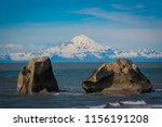 Volcanic Mount Redoubt and Cook Inlet with large boulders at low tide in Nikiski, Alaska