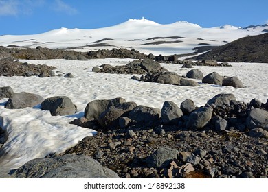 volcanic rocks and snow-capped mountain peak om a sunny day in snaefellsjokul, snaefellsnes national park,  iceland