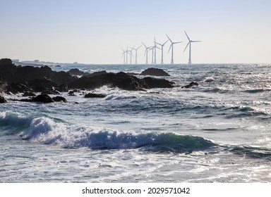 Volcanic rocks with wave against wind generator on the sea at Sinchang Windmill Beach near Jeju-si, Jeju-do, South Korea 
