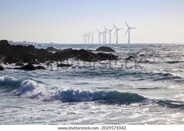 Volcanic rocks with wave against wind generator on the\
sea at Sinchang Windmill Beach near Jeju-si, Jeju-do, South Korea\
\

