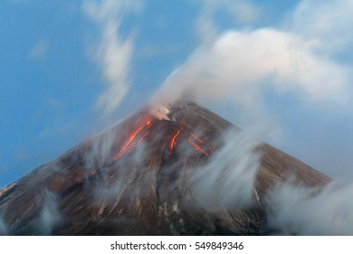 Volcano landscape of Kamchatka Peninsula: active Klyuchevskoy Volcano, view of top of a volcanic eruption - hot red glowing lava flows on slope of volcano; plume of gas, steam and ashes from crater. - Powered by Shutterstock