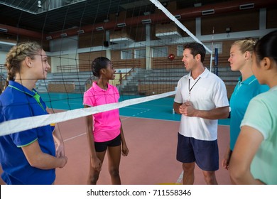 Volleyball coach talking to female players in court - Powered by Shutterstock