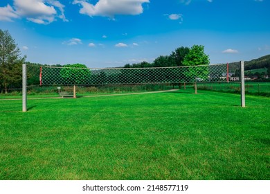 A Volleyball Court In A Park. Grass Volleyball Court. Play Sports Outdoors. A Volleyball Net In The Middle Of A Park With A Blue Sky