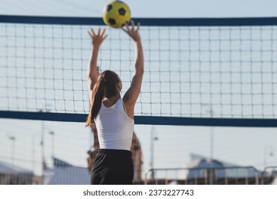 Volleyball game, female team of girls play volleyball, players on the outdoor playground with net and green lawn grass court, sports children team during the game, summer sunny - Powered by Shutterstock