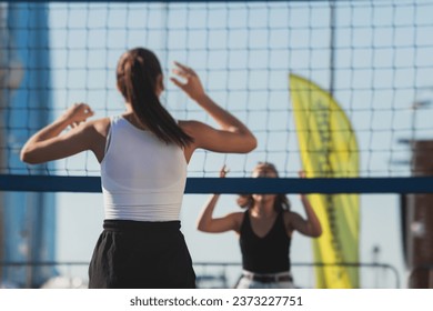 Volleyball game, female team of girls play volleyball, players on the outdoor playground with net and green lawn grass court, sports children team during the game, summer sunny - Powered by Shutterstock