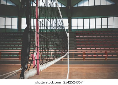 Volleyball net in an empty gymnasium with bleachers, parquet floor and large windows, waiting for the athletes to arrive - Powered by Shutterstock