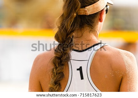 Volleyball player serving is a female beach volleyball player getting ready to serve the ball.