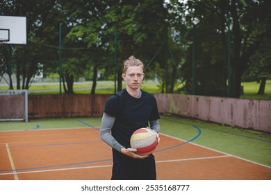 Volleyball player standing on a hard court, holding a ball with focus and determination before the game. The image captures a calm moment of preparation in an outdoor volleyball setting. - Powered by Shutterstock