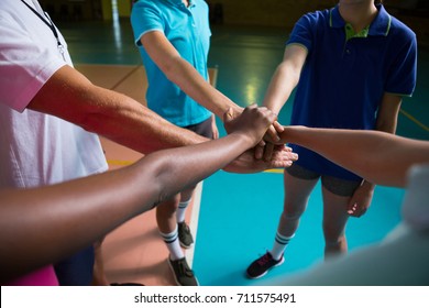 Volleyball players and coach forming hand stack in the court - Powered by Shutterstock