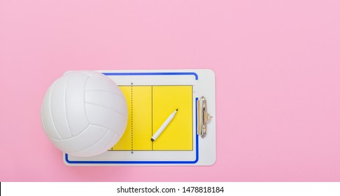 Volleyball and tactical board with marker on pink background. Top view