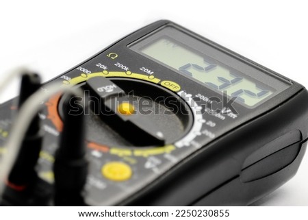 The voltmeter measures and shows a voltage of 232V on the display. Electric digital measuring tool. Multimeter.