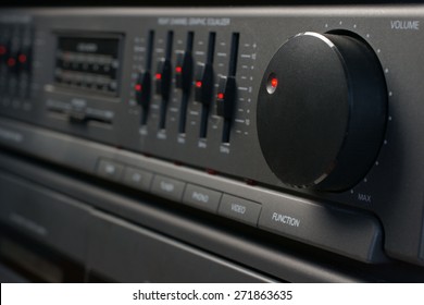 Volume and graphic equalizer controls on an audio system shot with low key light and selective focus
