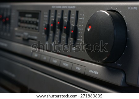 Volume and graphic equalizer controls on an audio system shot with low key light and selective focus