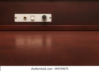 Volume knob and headphone jack on rich wooden desk