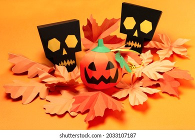 Volumetric paper skulls and Jack-o-lantern with autumn leaves. Real volumetric handmade paper objects. Paper art and craft. Holiday decorations for Halloween