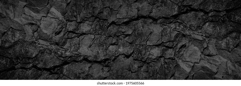 Volumetric rock texture with cracks. Black stone background with copy space for design. Wide banner. - Shutterstock ID 1975605566
