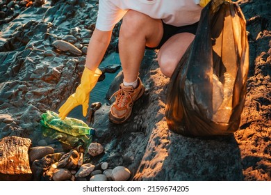Volunteer Activist Puts A Plastic Bottle In A Garbage Bag. Close-up. Top View. The Concept Of Environmental Conservation And Coastal Zone Cleaning.