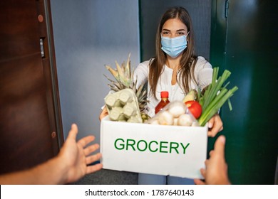 Volunteer Bringing Food To Old And Disability People In Quarantine. Food Delivery During Covid-19. Woman At Open Door Delivering Fresh Food In Box During Covid-19 Coronavirus Crisis Curfew Quarantine