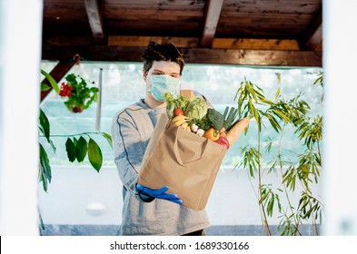 Volunteer Carrying Necessities For Citizens In Home Self Isolation.Young Man With Bag Of Groceries.Helping Senior People During Corona Virus Pandemic.Town In Quarantine Due To Covid-19 Flue Infection