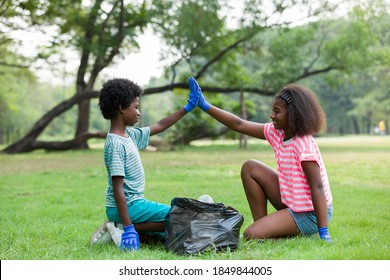 Volunteer children. Cheerful boy and girl in gloves holding black garbage bag with plastic bottles outdoor. Volunteer and charity concept - Powered by Shutterstock