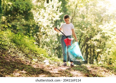 Volunteer cleaning up the forest, she is collecting trash and holding a garbage bag, environmental protection concept - Powered by Shutterstock