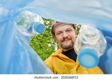 Volunteer Collecting Litter Picking Up Trash Plastic Bottle In Garbage Bag. Picking Up Garbage Plastic Bag. Volunteer Cleaning Park View From Inside A Trash Bag. Altruistic Man Collect Garbage Forest