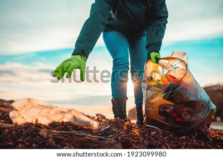 A volunteer collects garbage on a muddy beach. Close-up. The concept of Earth Day. Bottom view.