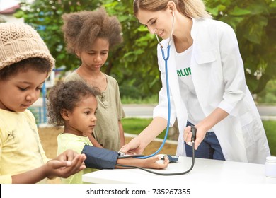 Volunteer Doctor Measuring Blood Pressure Of African Child Outdoors