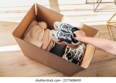 Volunteer with donations for poor people. Cardboard box with clothes for charity. Help poor. Woman holding a donate box. Case full of clothing for poor giving. Sharity social activity.