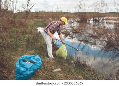 Volunteer and environmental activist cleaning dirty lake shore filled with trash.