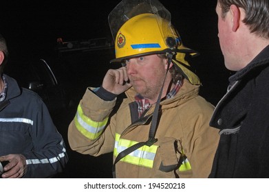 Volunteer fire fighter relays messages on a mobile phone during an evening bushfire, Westland, New Zealand