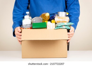 Volunteer hands holding cardbox with grocery products. Volunteer collecting food into donation box. Donation, charity, food bank, help for poor families, migrants, refugees